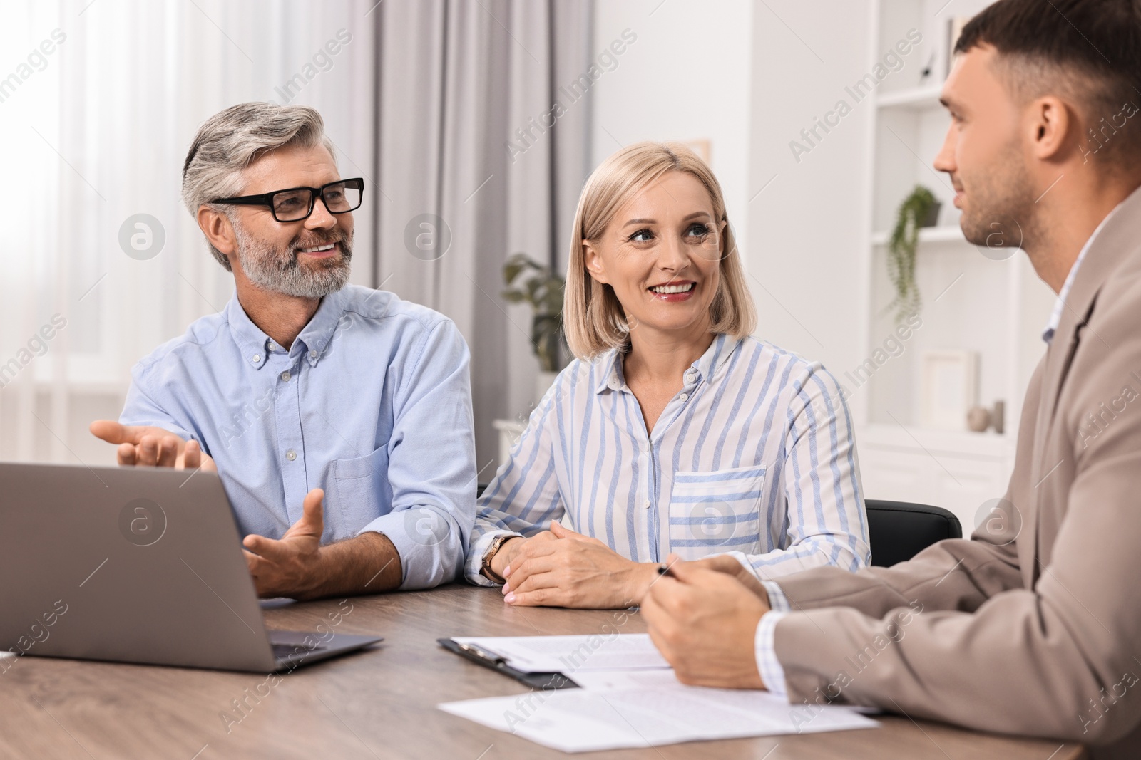 Photo of Pension plan. Couple consulting with insurance agent at table indoors