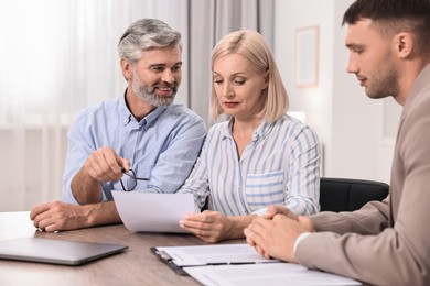 Pension plan. Couple consulting with insurance agent at table indoors