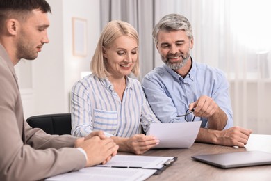 Pension plan. Couple consulting with insurance agent at table indoors