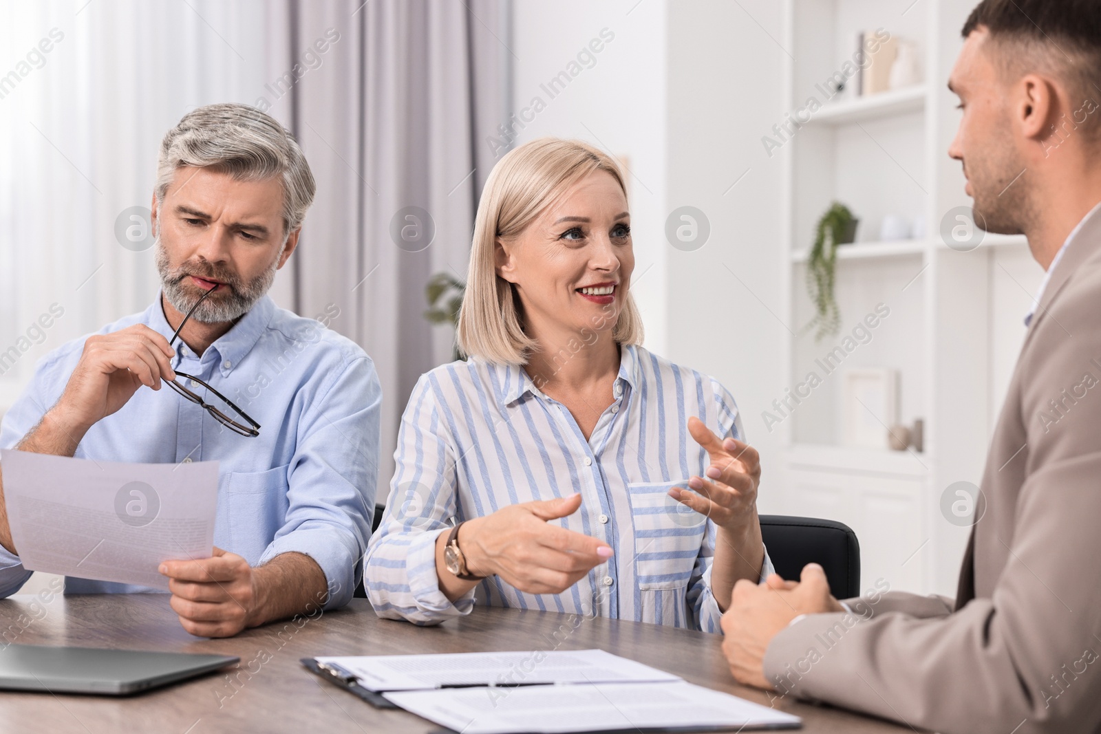 Photo of Pension plan. Couple consulting with insurance agent at table indoors