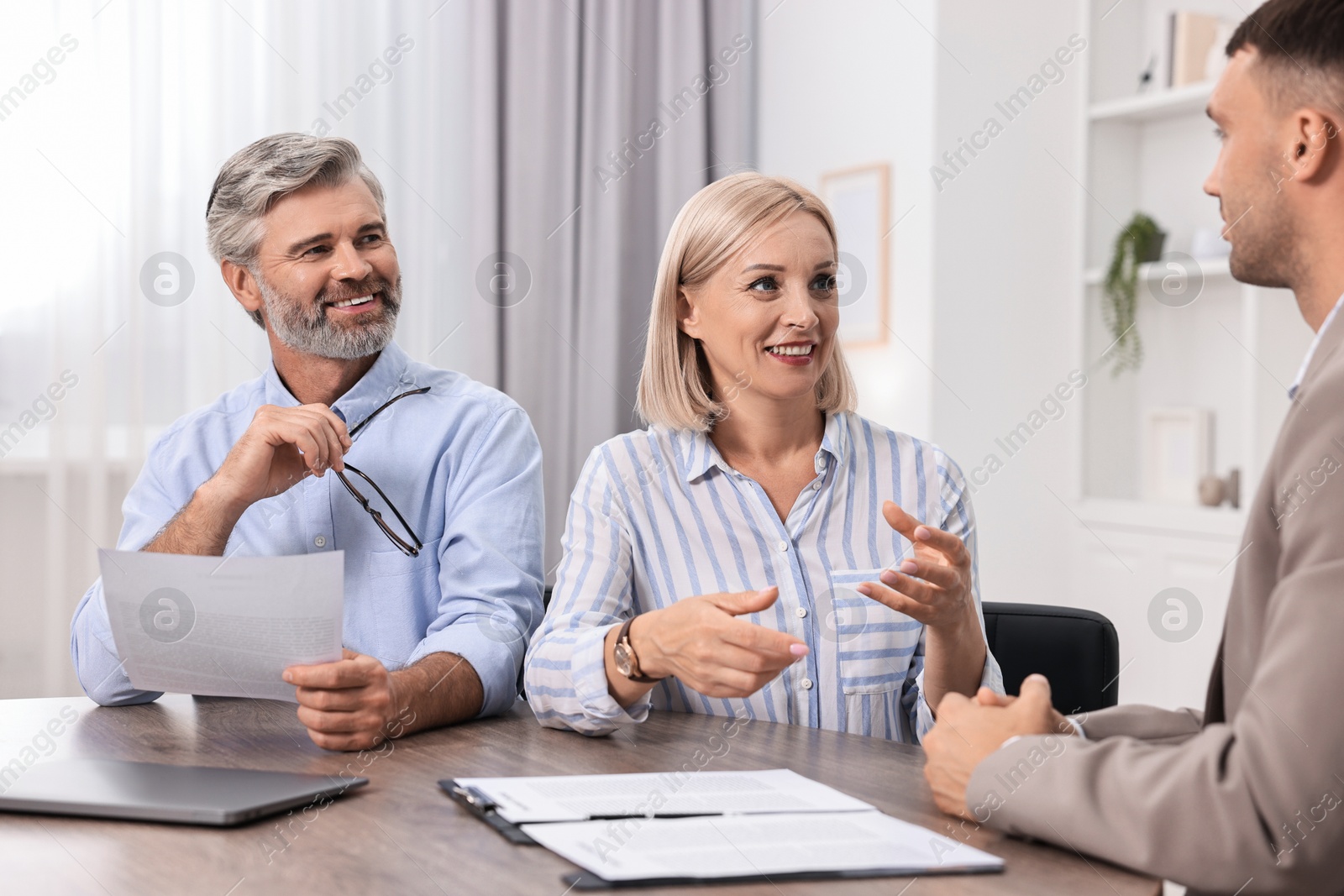 Photo of Pension plan. Couple consulting with insurance agent at table indoors