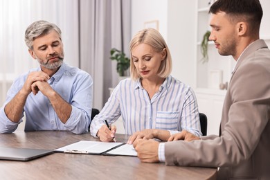 Photo of Pension plan. Couple consulting with insurance agent at table indoors