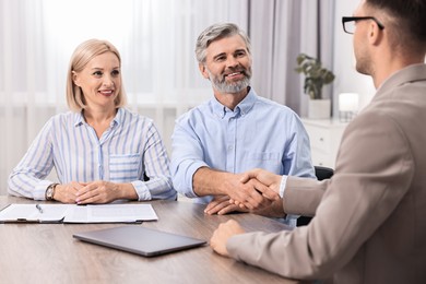 Photo of Pension plan. Couple consulting with insurance agent at table indoors