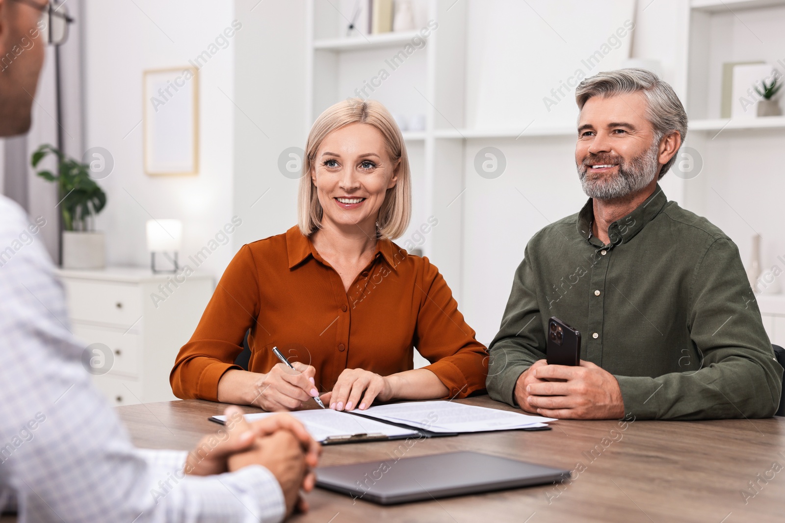 Photo of Pension plan. Couple consulting with insurance agent at table indoors