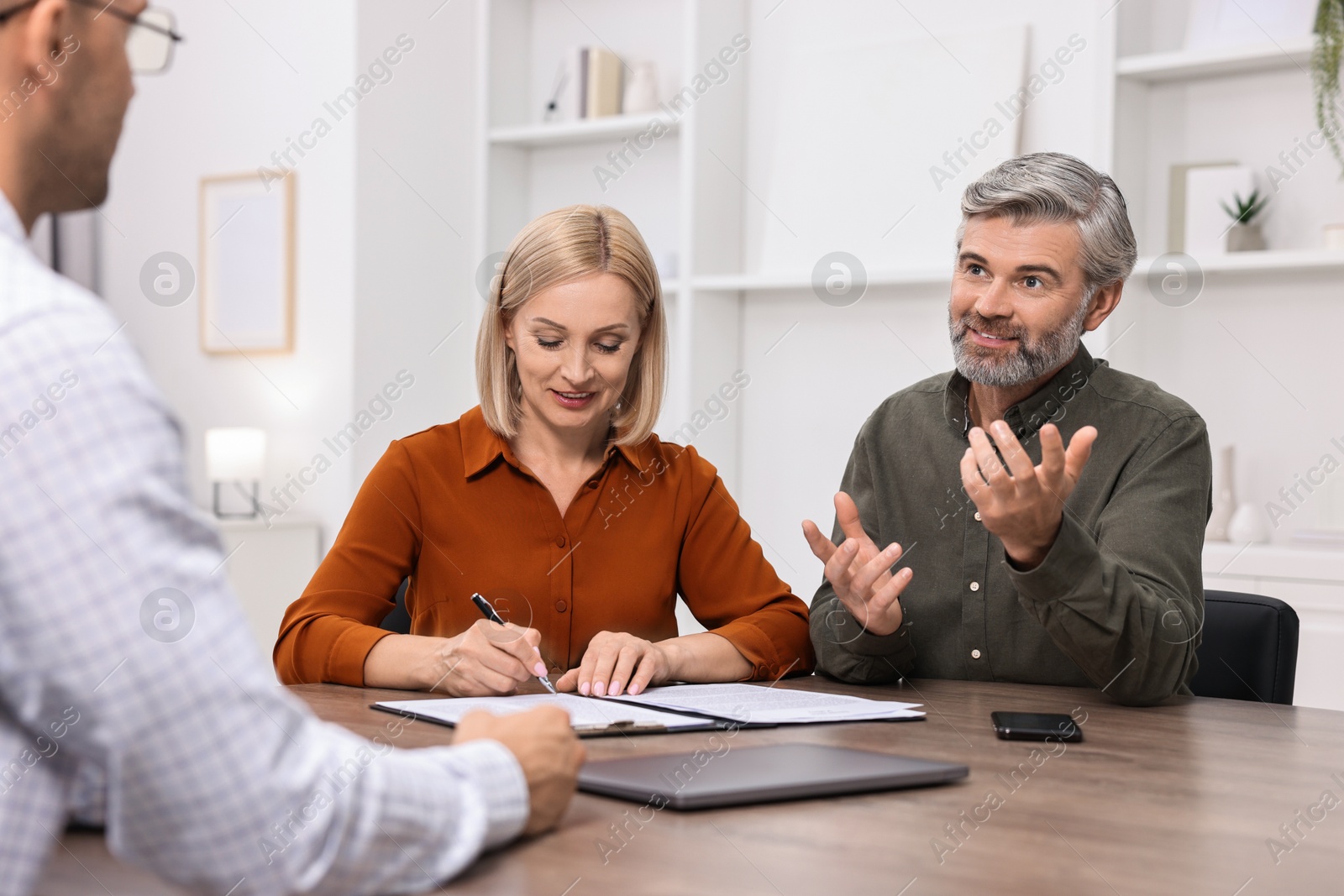 Photo of Pension plan. Couple consulting with insurance agent at table indoors