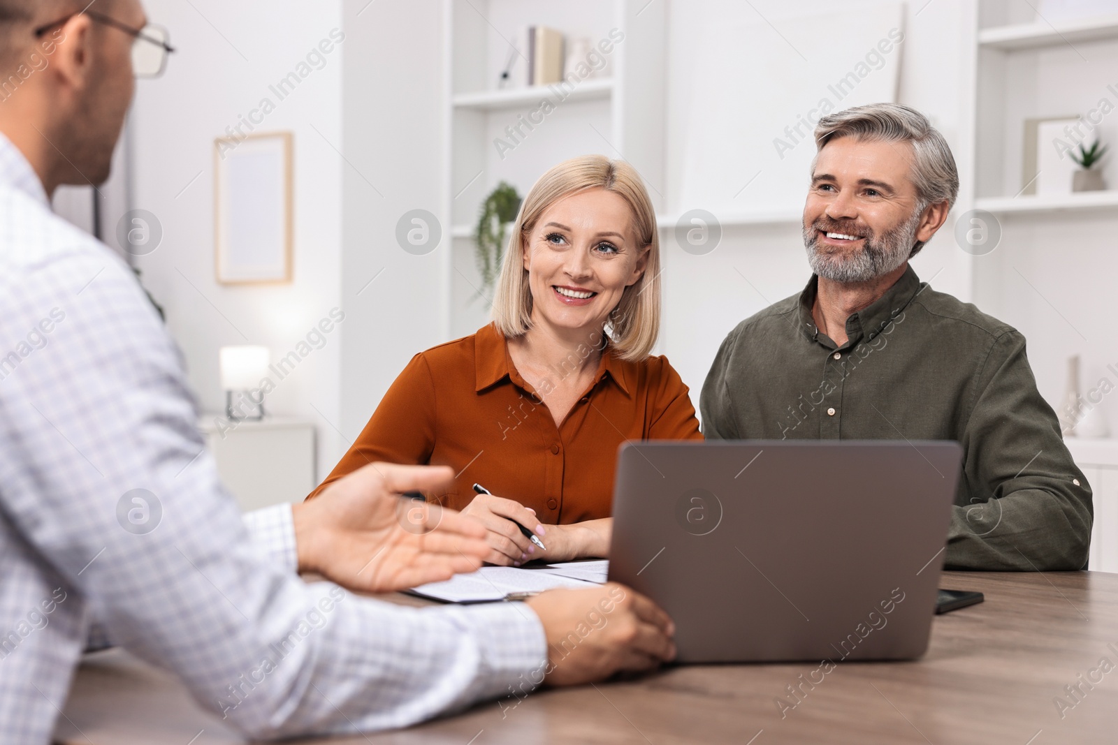 Photo of Pension plan. Couple consulting with insurance agent at table indoors