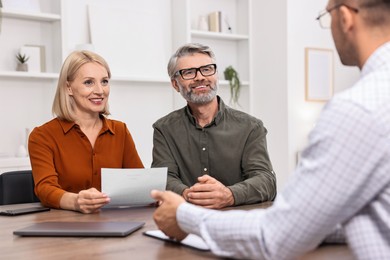 Pension plan. Couple consulting with insurance agent at table indoors