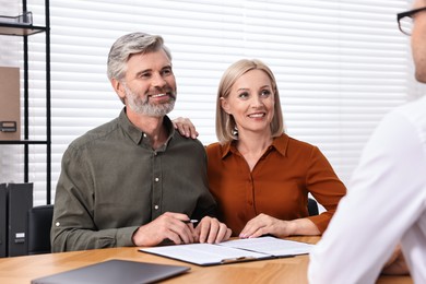 Pension plan. Couple consulting with insurance agent at table indoors