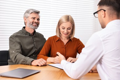 Pension plan. Couple consulting with insurance agent at table indoors