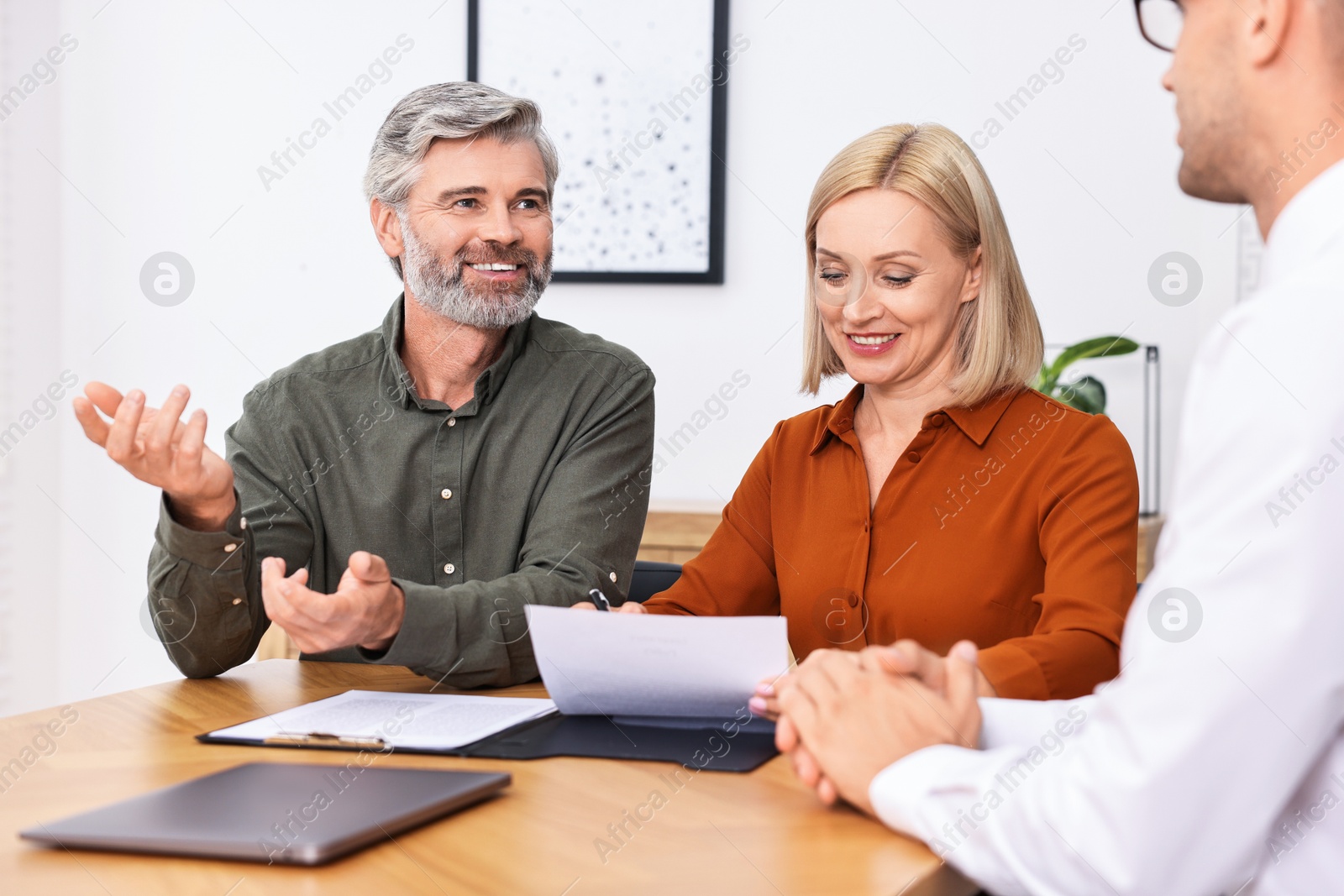 Photo of Pension plan. Couple consulting with insurance agent at table indoors