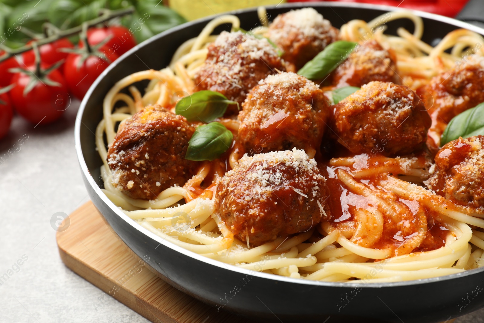 Photo of Delicious pasta with meatballs and ingredients on light grey table, closeup