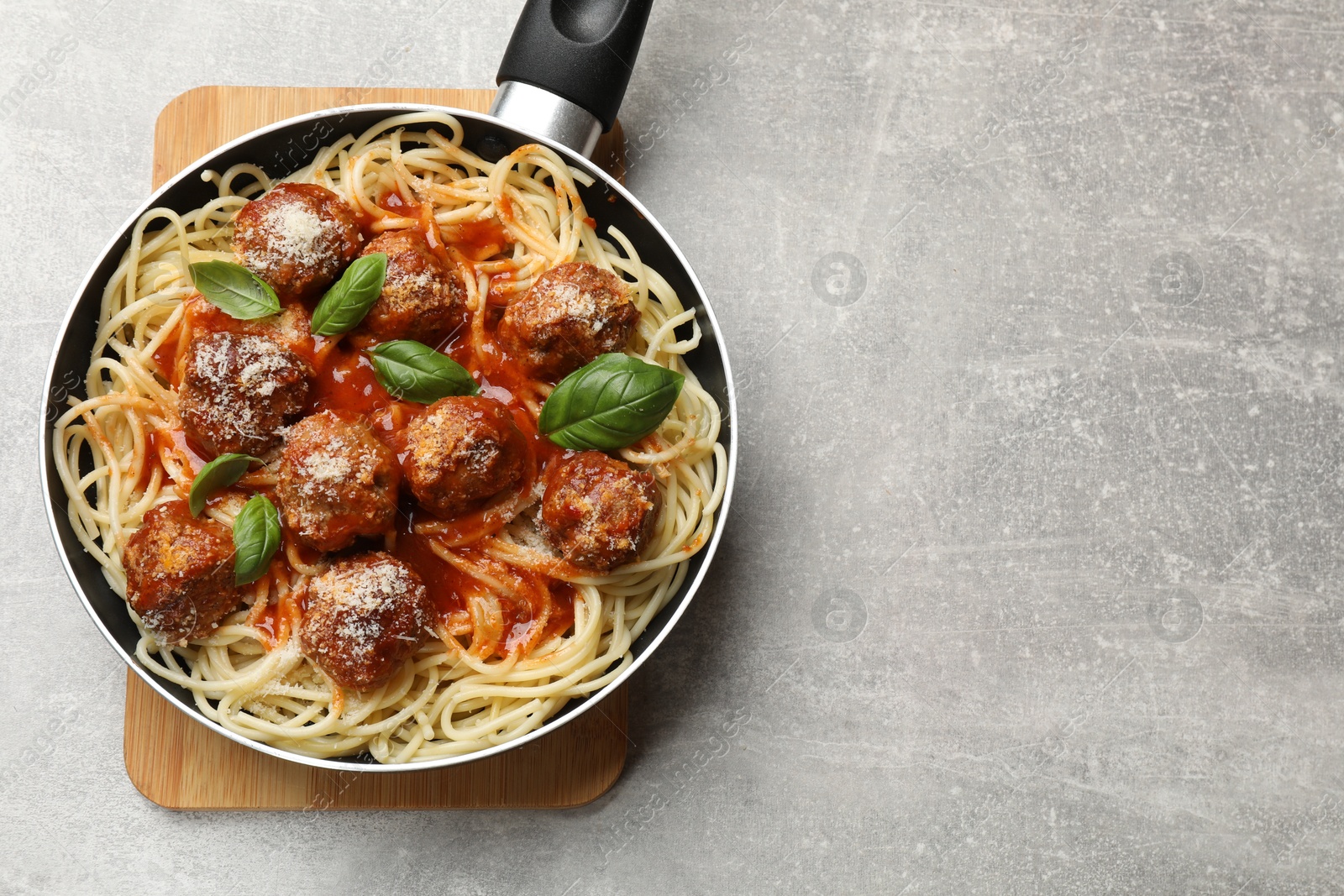 Photo of Delicious pasta with meatballs on light grey table, top view. Space for text