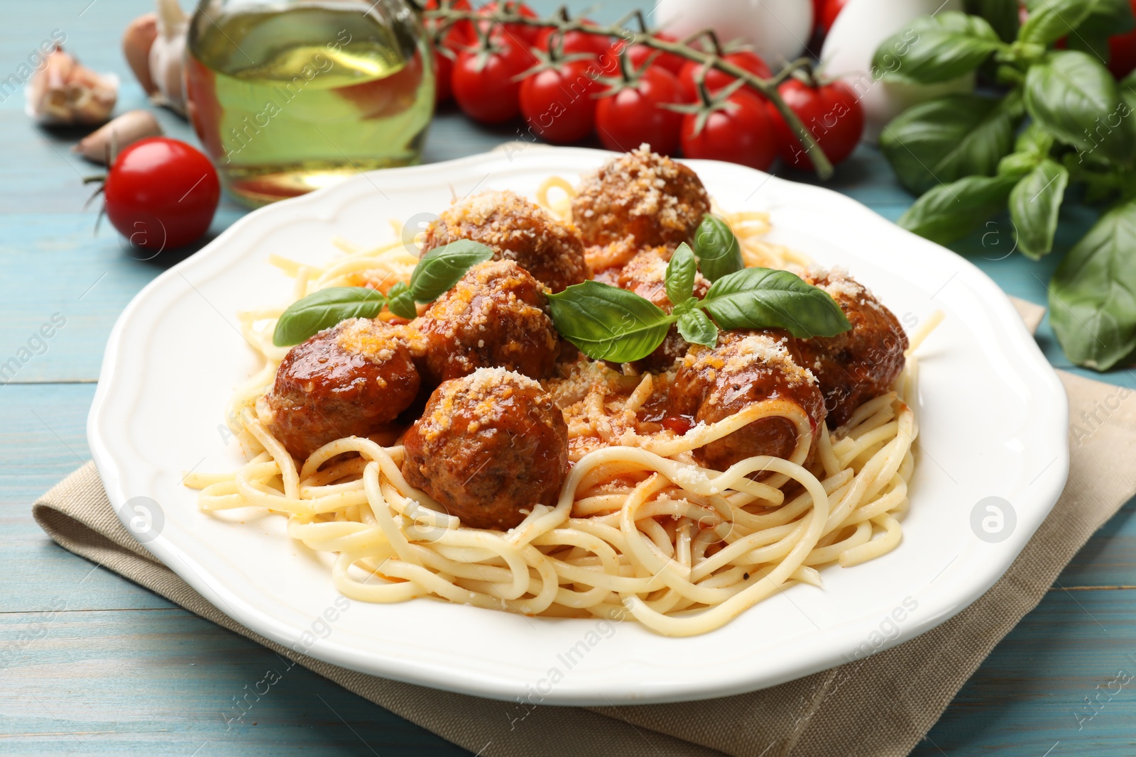 Photo of Delicious pasta with meatballs and ingredients on light blue wooden table, closeup