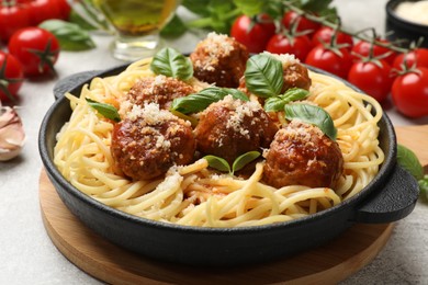 Delicious pasta with meatballs and ingredients on light grey table, closeup