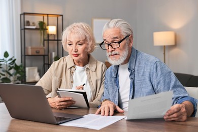 Photo of Pension savings. Senior couple planning budget at wooden table indoors