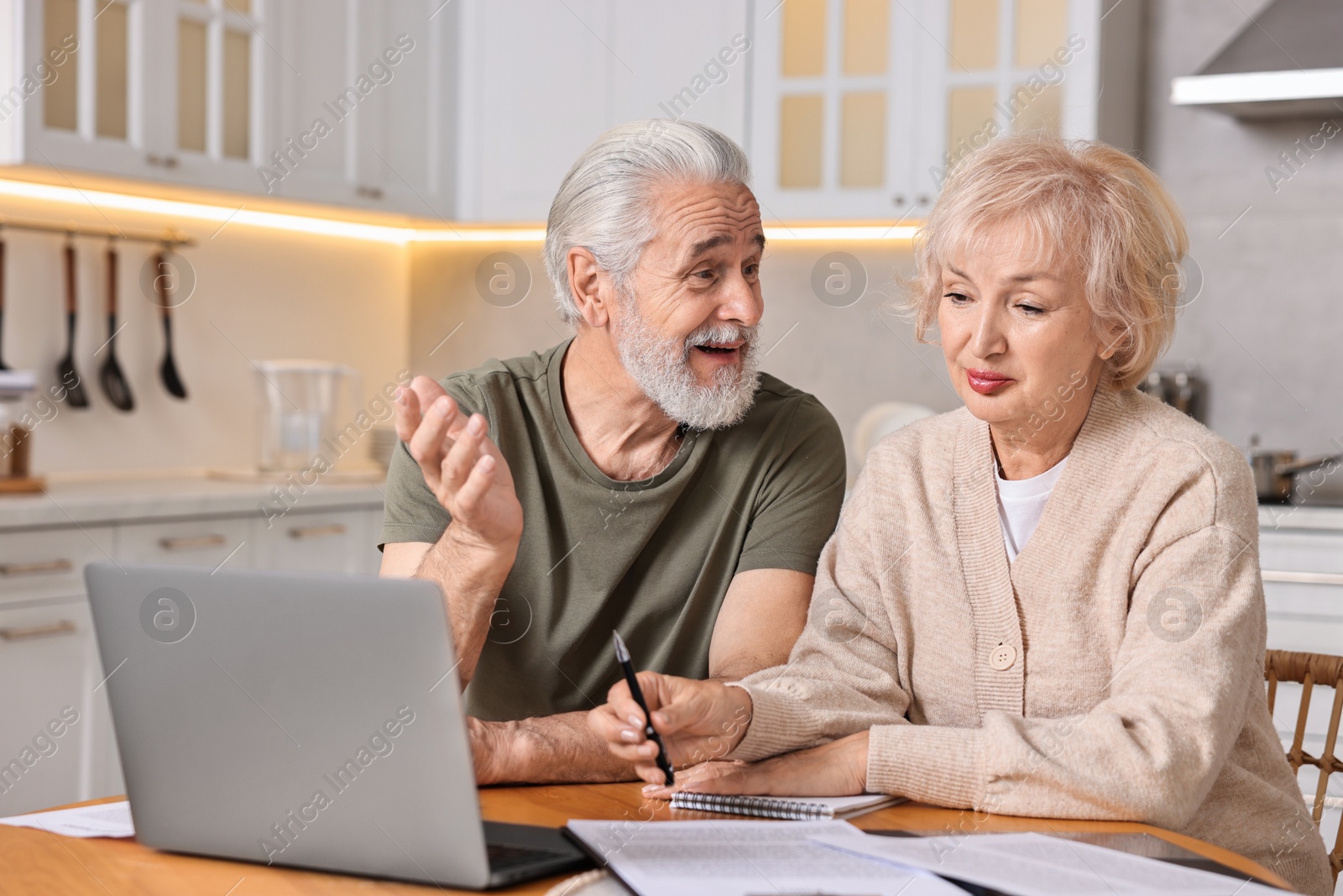 Photo of Pension savings. Senior couple planning budget at wooden table indoors