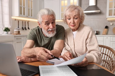 Photo of Pension savings. Senior couple planning budget at wooden table indoors