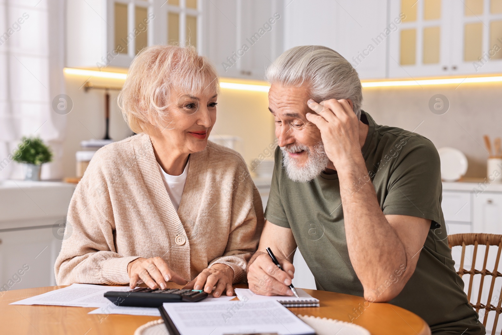 Photo of Pension savings. Senior couple planning budget at wooden table indoors