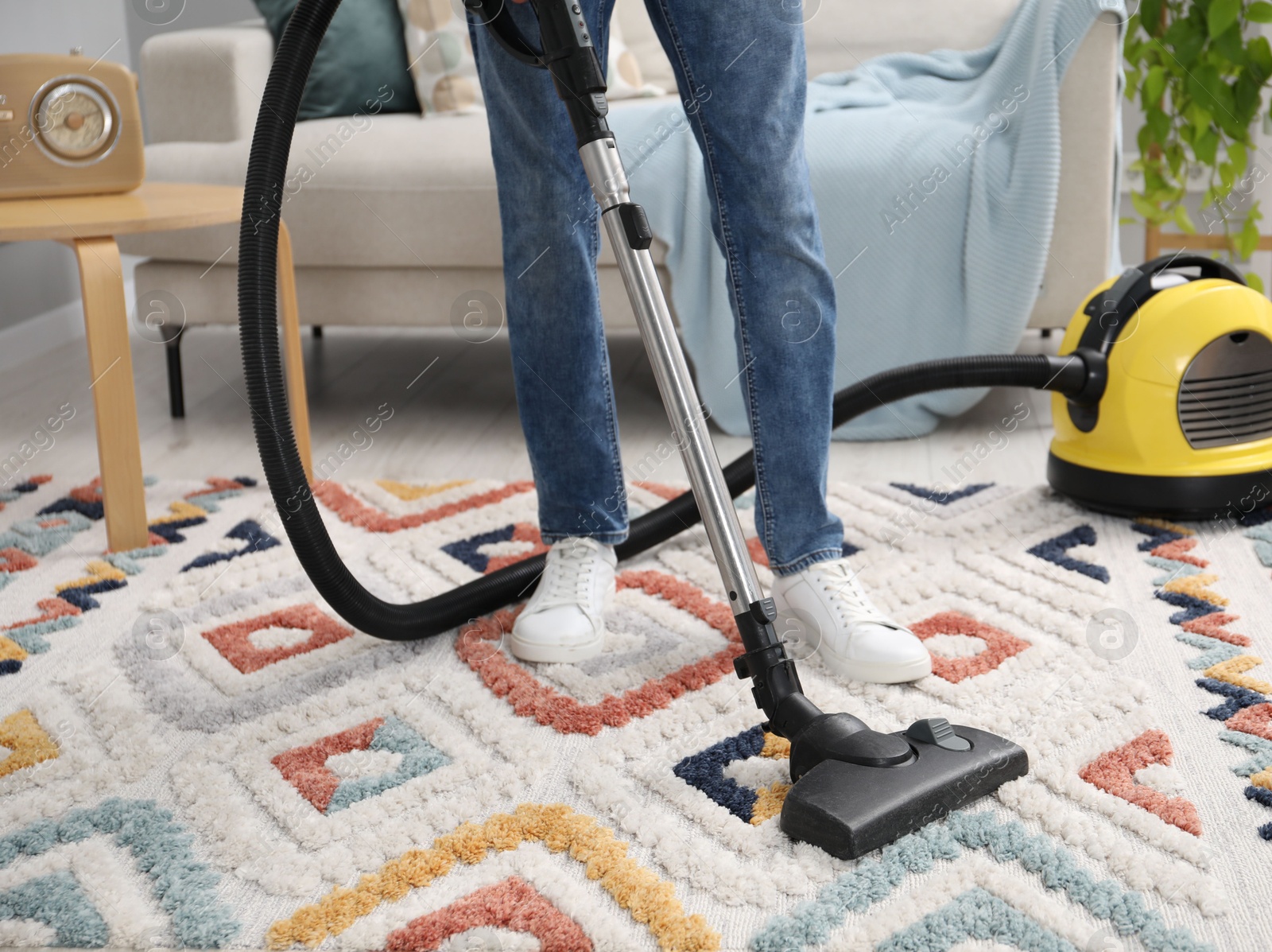 Photo of Man with vacuum cleaning carpet in living room, closeup