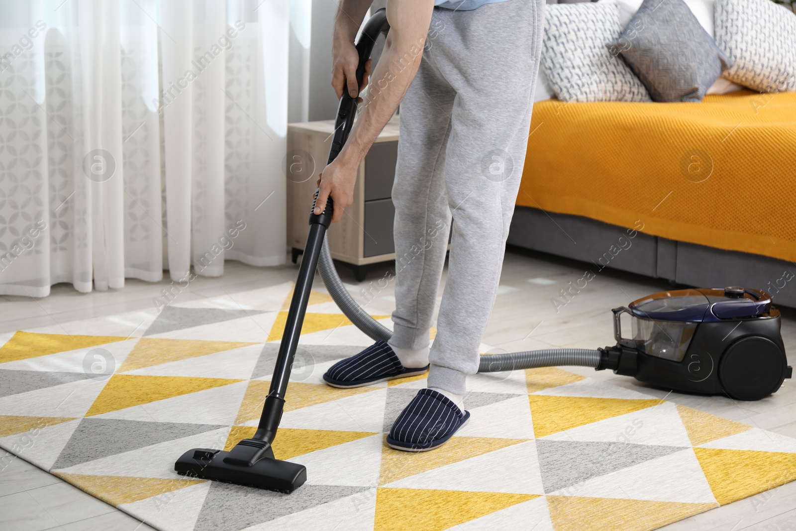 Photo of Man with vacuum cleaning carpet in bedroom, closeup