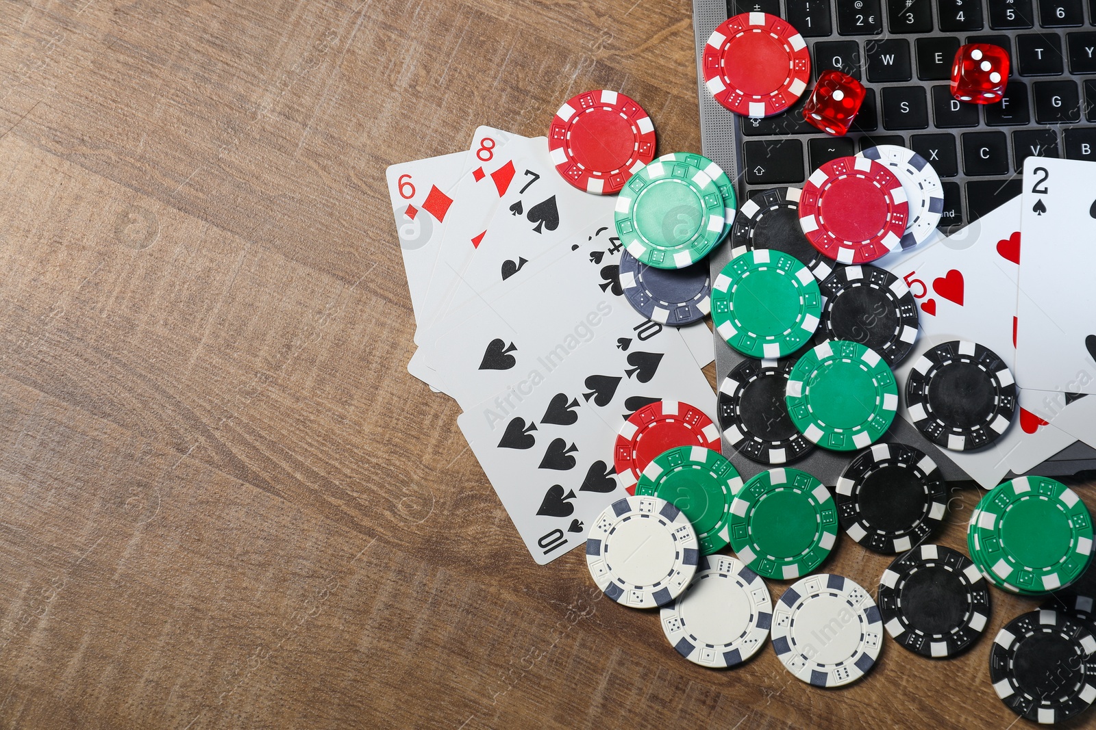 Photo of Online game. Poker chips, laptop, playing cards and dices on wooden table, flat lay. Space for text