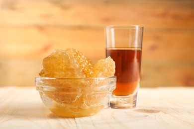 Photo of Honey tincture and honeycombs on light wooden table, closeup. Alternative medicine