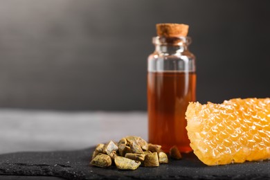 Photo of Honey tincture, honeycomb and pile of propolis granules on table, closeup. Space for text