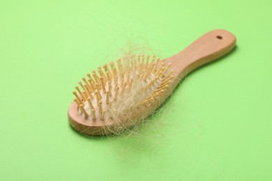 Photo of One brush with lost hair on light green background. Alopecia problem