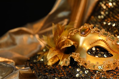 Beautiful carnival mask on golden fabric, closeup