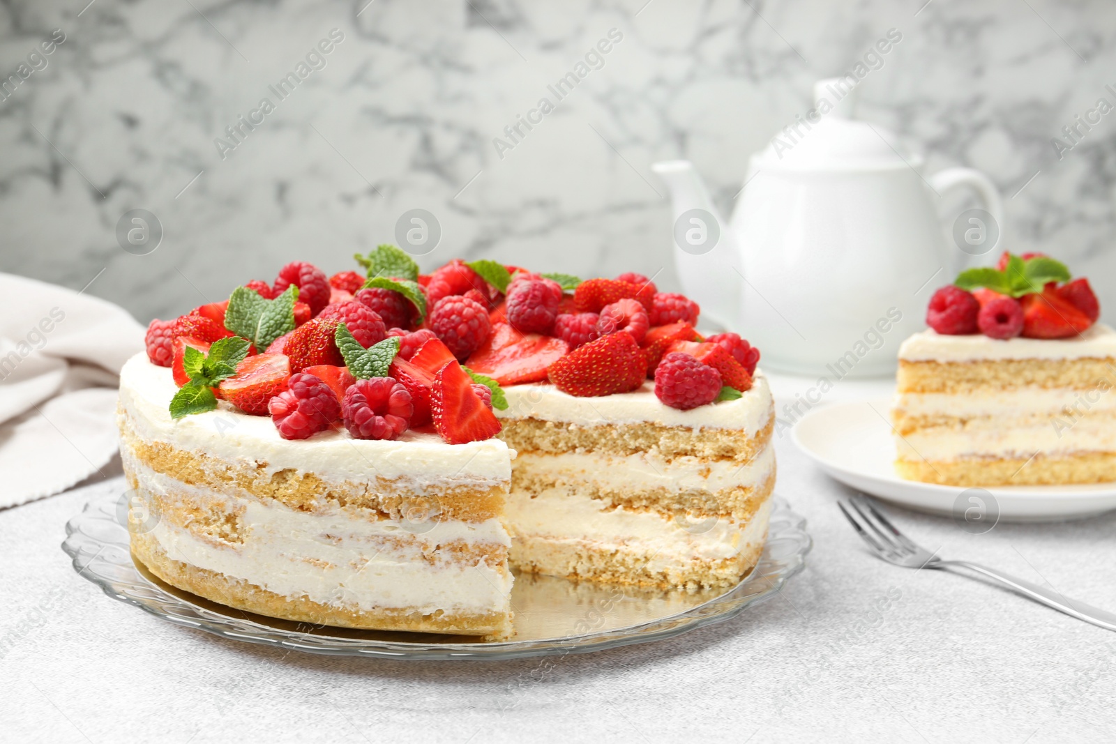 Photo of Tasty sponge cake with fresh berries and mint on light gray table