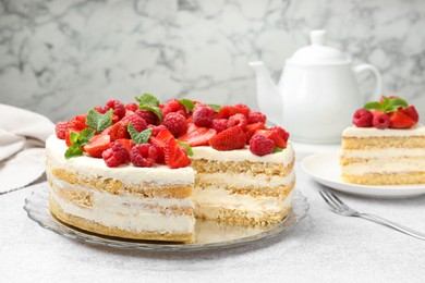 Photo of Tasty sponge cake with fresh berries and mint on light gray table