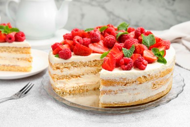 Photo of Tasty sponge cake with fresh berries and mint on light gray table, closeup