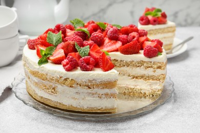 Photo of Tasty sponge cake with fresh berries and mint on light gray table, closeup