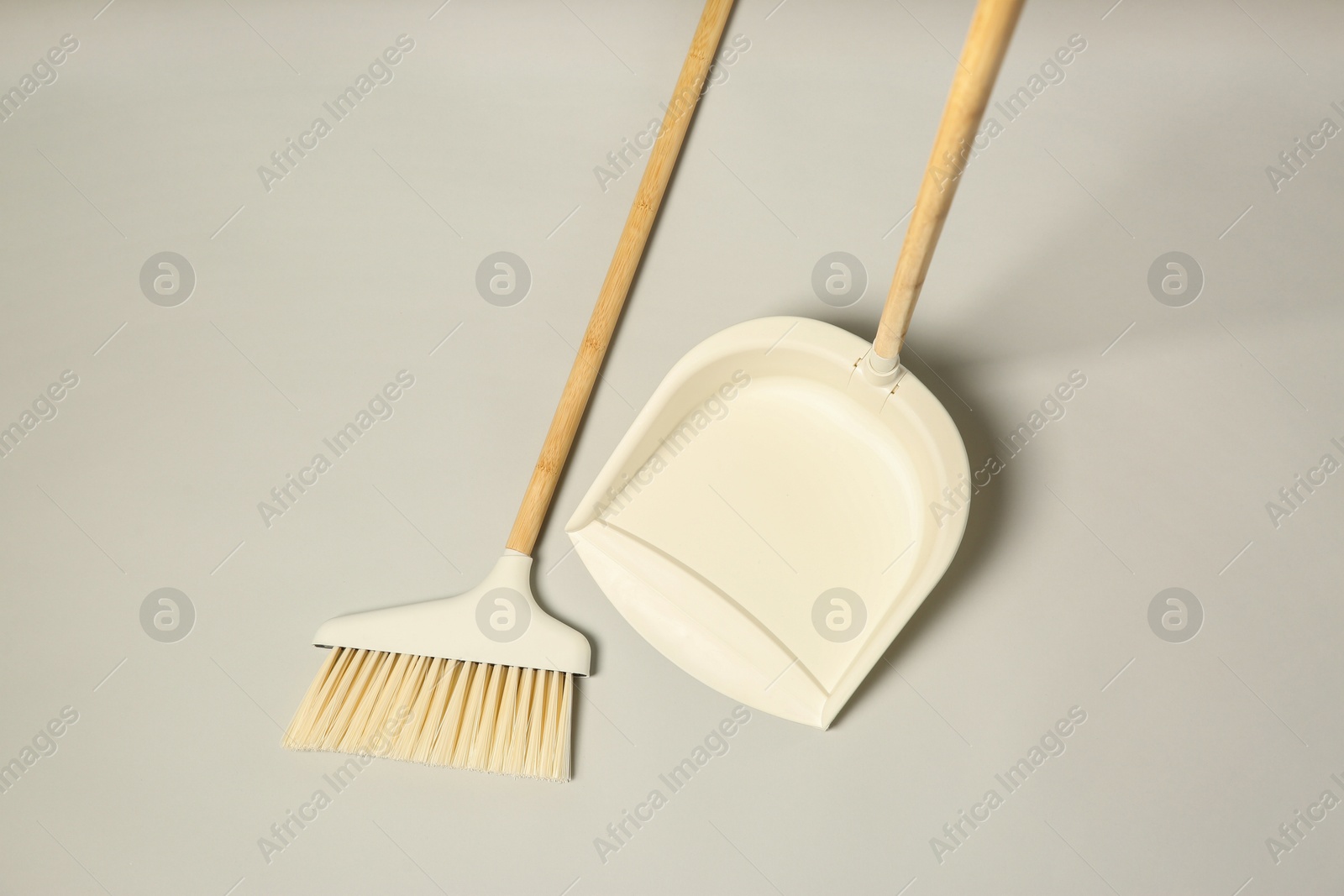 Photo of Cleaning broom and dustpan on grey background, flat lay