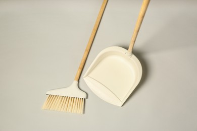 Cleaning broom and dustpan on grey background, flat lay