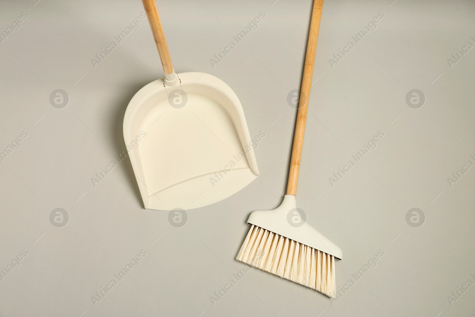 Photo of Cleaning broom and dustpan on grey background, flat lay