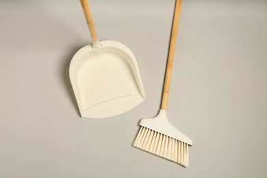 Photo of Cleaning broom and dustpan on grey background, flat lay