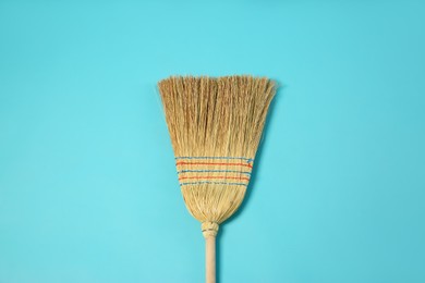 Photo of One corn straw broom on light blue background, top view