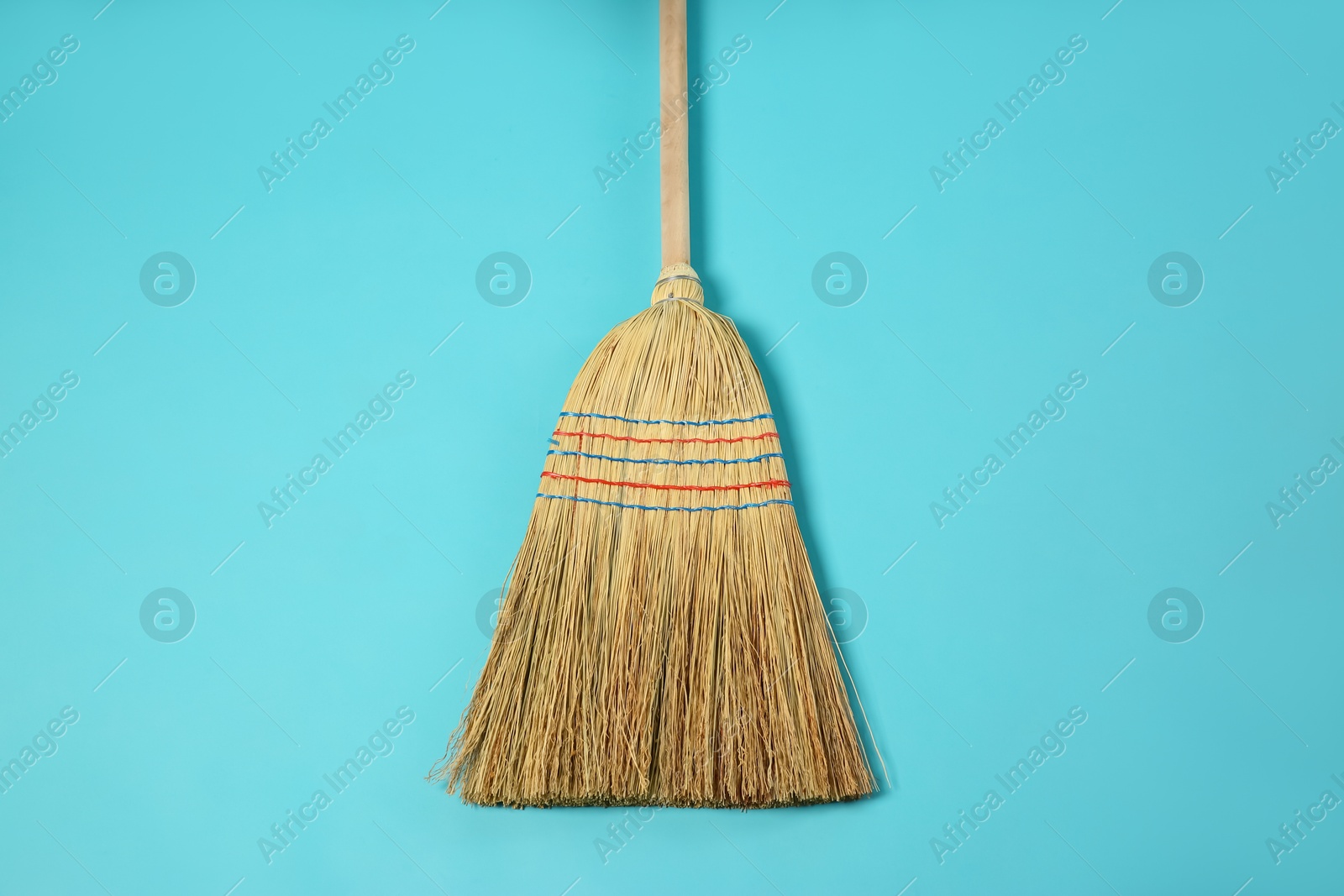 Photo of One corn straw broom on light blue background, top view