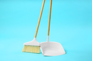 Photo of Cleaning broom and dustpan on light blue background