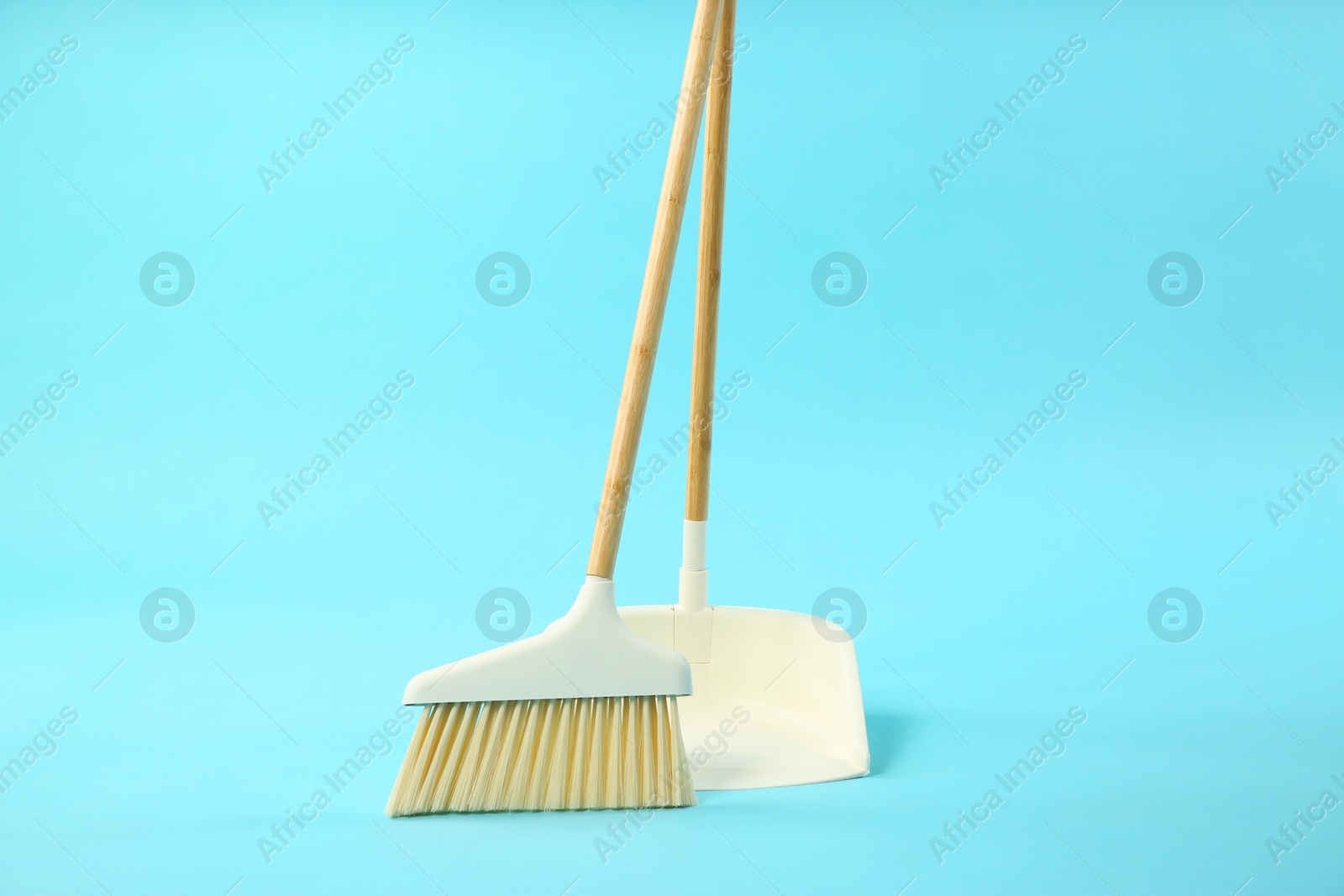 Photo of Cleaning broom and dustpan on light blue background