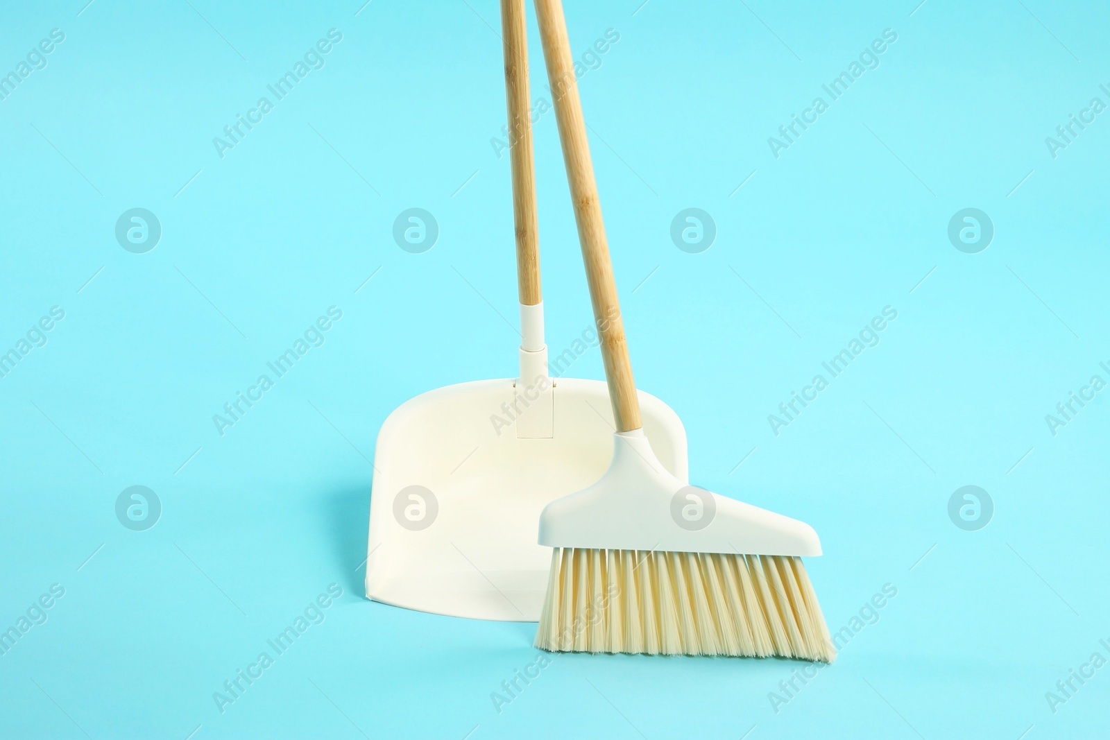 Photo of Cleaning broom and dustpan on light blue background