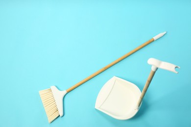 Photo of Cleaning broom and dustpan on light blue background, flat lay