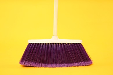 Photo of One bright cleaning broom on yellow background