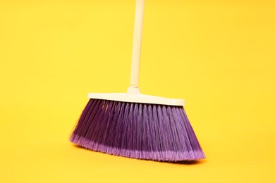 Photo of One bright cleaning broom on yellow background