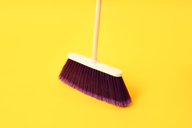 Photo of One bright cleaning broom on yellow background