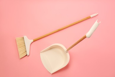 Cleaning broom and dustpan on pink background, flat lay