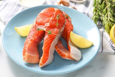 Photo of Plate with fresh salmon steaks, lemon and thyme on white marble table, closeup