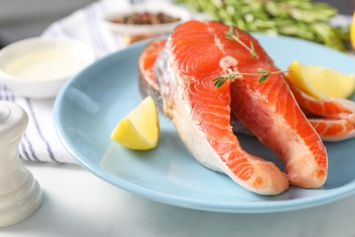 Photo of Plate with fresh salmon steaks, lemon and thyme on white marble table, closeup