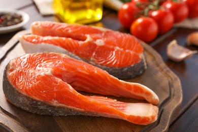 Photo of Board with fresh salmon steaks on table, closeup